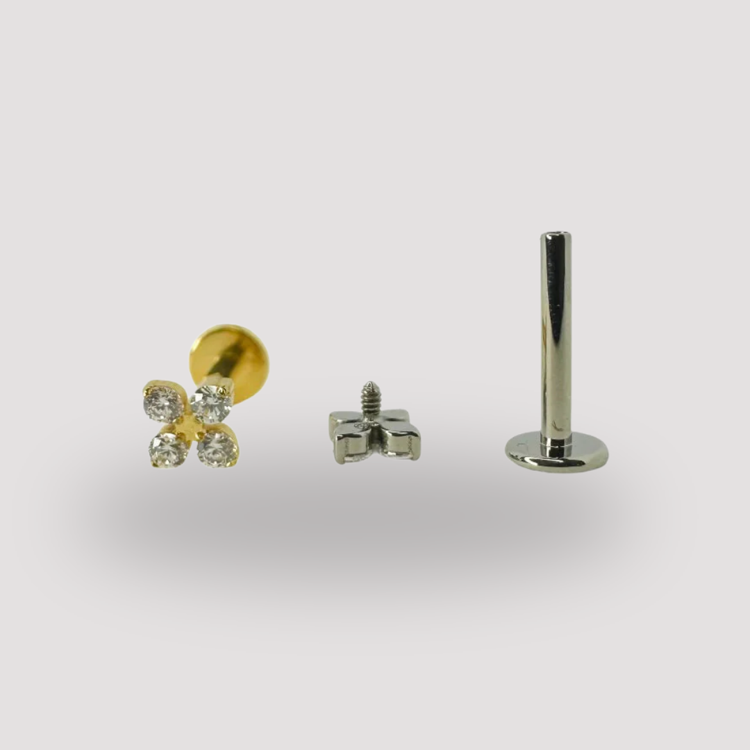 Stud piercing en titane Héra Jewelry, composé d’une tige plate argentée, d’un pas de vis et d’un embout doré en forme de fleur sertie de zircons scintillants, hypoallergénique et élégant.