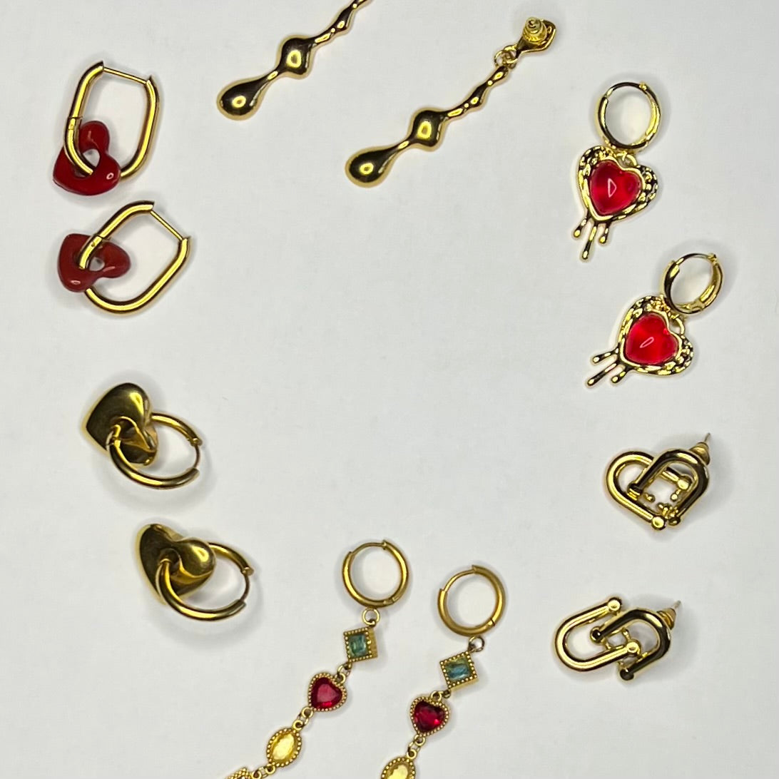 Collection de boucles d’oreilles Héra Jewelry présentées sur fond blanc : créoles avec pendentifs cœurs rouges, modèles géométriques, boucles pendantes et designs modernes, bijoux femme tendance